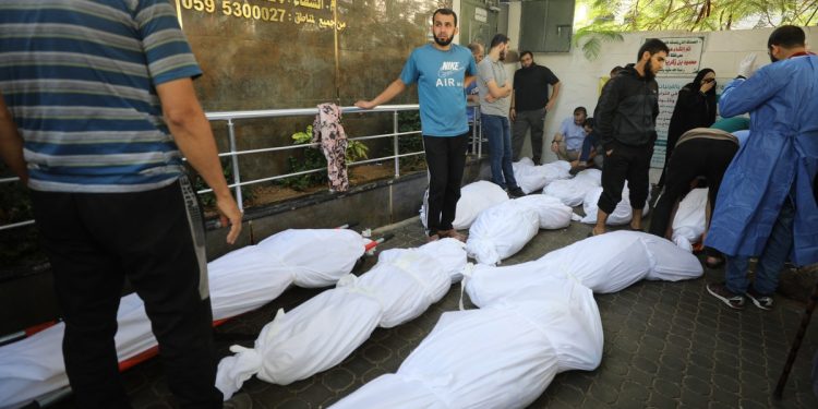 Personas junto a los cuerpos envueltos de las víctimas que murieron en los bombardeos israelíes mientras yacen afuera del hospital Al-Shifa en la ciudad de Gaza el 8 de noviembre de 2023, en medio de las batallas en curso entre Israel y el movimiento palestino Hamas. (Foto de Dawood NEMER / AFP)