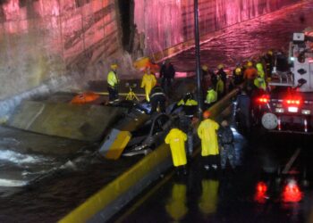Los rescatistas buscan personas atrapadas debajo de un muro que se derrumbó sobre varios vehículos tras las fuertes lluvias en la avenida 27 de febrero de Santo Domingo el 18 de noviembre de 2023. (Foto de Félix León/AFP)
