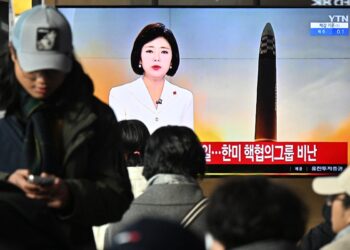 La gente se sienta cerca de una pantalla de televisión que muestra una transmisión de noticias con imágenes de archivo de una prueba de misil norcoreano, en una estación de tren en Seúl el 18 de diciembre de 2023. - Corea del Norte disparó otro "misil balístico de largo alcance" prohibido internacionalmente el 18 de diciembre de 2023. dijo el ejército del Sur, después de que Pyongyang expresara su indignación por una cooperación nuclear más profunda entre Seúl y Washington. (Foto de Anthony WALLACE / AFP)