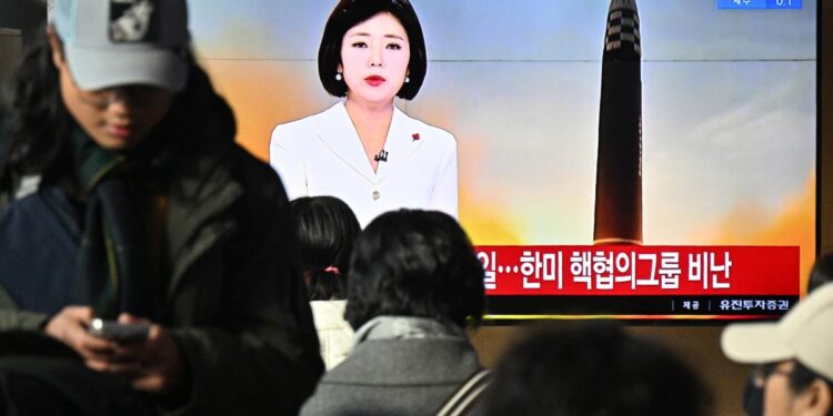 La gente se sienta cerca de una pantalla de televisión que muestra una transmisión de noticias con imágenes de archivo de una prueba de misil norcoreano, en una estación de tren en Seúl el 18 de diciembre de 2023. - Corea del Norte disparó otro "misil balístico de largo alcance" prohibido internacionalmente el 18 de diciembre de 2023. dijo el ejército del Sur, después de que Pyongyang expresara su indignación por una cooperación nuclear más profunda entre Seúl y Washington. (Foto de Anthony WALLACE / AFP)