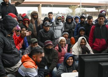 Venezuelan migrants gather around a small tv near the US-Mexico border to watch the Qatar 2022 World Cup Final football match between Argentina and France in Juarez, Mexico, on December 18, 2022. (Photo by Patrick T. Fallon / AFP) / The erroneous mention[s] appearing in the metadata of this photo by Patrick T. Fallon has been modified in AFP systems in the following manner: the location in the photos should be [Juarez, Mexico,] instead of [El Paso, Texas,]. Please immediately remove the erroneous mention[s] from all your online services and delete it (them) from your servers. If you have been authorized by AFP to distribute it (them) to third parties, please ensure that the same actions are carried out by them. Failure to promptly comply with these instructions will entail liability on your part for any continued or post notification usage. Therefore we thank you very much for all your attention and prompt action. We are sorry for the inconvenience this notification may cause and remain at your disposal for any further information you may require.