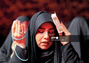 Una mujer reza durante una reunión con otros devotos para las oraciones rituales de Laylat al-Qadr (Noche del Destino), una de las noches más sagradas durante el mes de ayuno musulmán del Ramadán, frente a la mezquita Imamzadeh Saleh en Teherán, el 10 de abril de 2023. (Foto de ATTA KENARE / AFP)