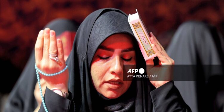Una mujer reza durante una reunión con otros devotos para las oraciones rituales de Laylat al-Qadr (Noche del Destino), una de las noches más sagradas durante el mes de ayuno musulmán del Ramadán, frente a la mezquita Imamzadeh Saleh en Teherán, el 10 de abril de 2023. (Foto de ATTA KENARE / AFP)
