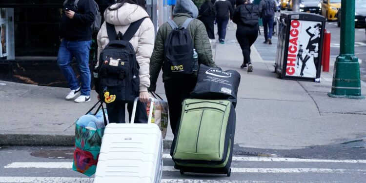 Una familia migrante sale del Row Hotel en Midtown Manhattan el 10 de enero de 2024. - La ciudad de Nueva York está iniciando el proceso de desalojar a las familias migrantes de los refugios administrados por la ciudad si han estado viviendo allí durante más de 60 días. (Foto de TIMOTHY A. CLARY / AFP)