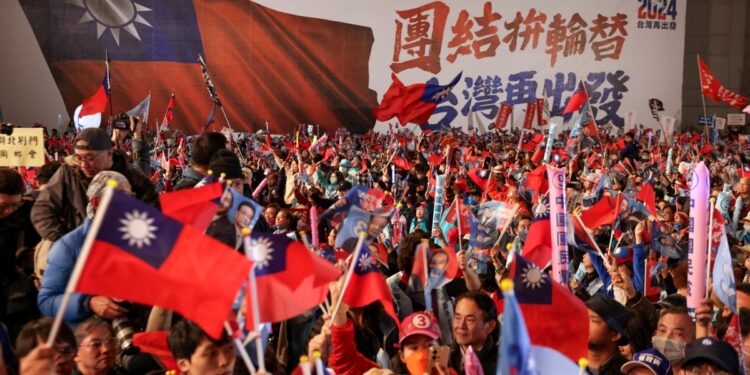 Simpatizantes que portan banderas nacionales vitorean durante un mitin de campaña electoral del Kuomintang (KMT) en la ciudad de Nuevo Taipei el 12 de enero de 2024. (Foto de I-Hwa CHENG / AFP)