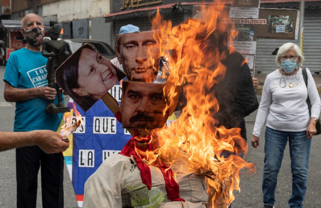 Los opositores al gobierno del presidente venezolano Nicolás Maduro queman un muñeco con las imágenes de Maduro (C-Abajo), el Presidente ruso Vladimir Putin (C-Arriba) y la alcaldesa de Caracas Carmen Meléndez (L) durante la tradicional "quema de Judas" dentro en el marco de la celebración de la Semana Santa en el barrio La Candelaria de Caracas, el 17 de abril de 2022. (Foto de Yuri CORTEZ/AFP)