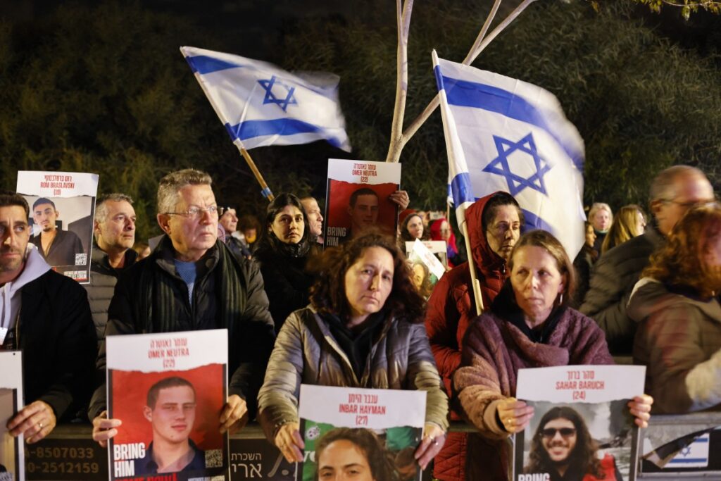 Los manifestantes levantan banderas nacionales y retratos de israelíes mantenidos como rehenes por militantes palestinos de Hamas en Gaza desde el 7 de octubre, durante una manifestación exigiendo su liberación frente a la residencia privada del primer ministro israelí Benjamín Netanyahu en Cesarea, al norte de Tel Aviv, el 27 de enero de 2024. (Foto de Marco LONGARI /AFP)