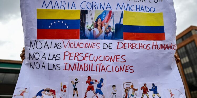 Un partidario de la líder de la oposición venezolana María Corina Machado sostiene un cartel que dice "No a las violaciones de derechos humanos. No a las persecuciones. No a las descalificaciones" durante una protesta en Bogotá el 4 de febrero de 2024. - Machado insistió el 29 de enero en que las elecciones no pueden continuar sin su nombre en la boleta, ya que Estados Unidos anunció que volvería a imponer algunas sanciones contra el país tras su descalificación. (Foto de Luis ACOSTA/AFP)