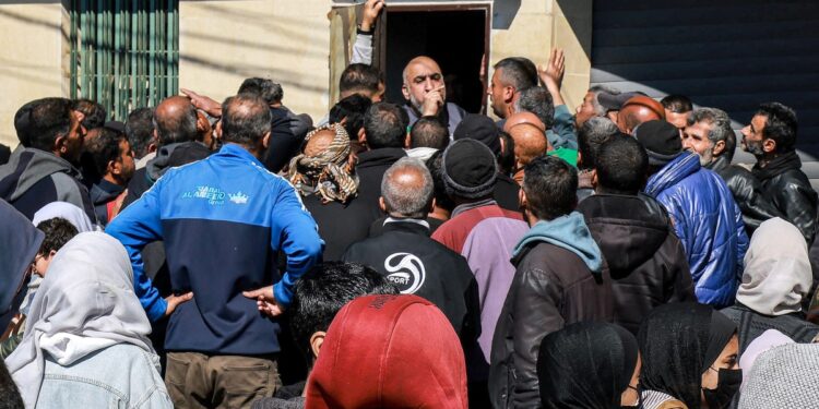 La gente se agolpa mientras hace cola para recibir sus salarios frente a una sucursal del Banco al-Quds en Rafah, en el sur de la Franja de Gaza, el 8 de febrero de 2024, en medio del conflicto en curso entre Israel y el grupo militante palestino Hamás. (Foto de Mohammed ABED / AFP)