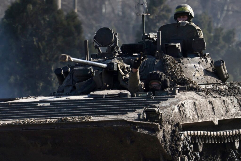 Un militar ucraniano hace el signo de la victoria desde un vehículo blindado de combate en una carretera de la región de Donetsk, en medio de la invasión rusa de Ucrania, el 17 de febrero de 2024. (Foto de Anatolii STEPANOV / AFP)