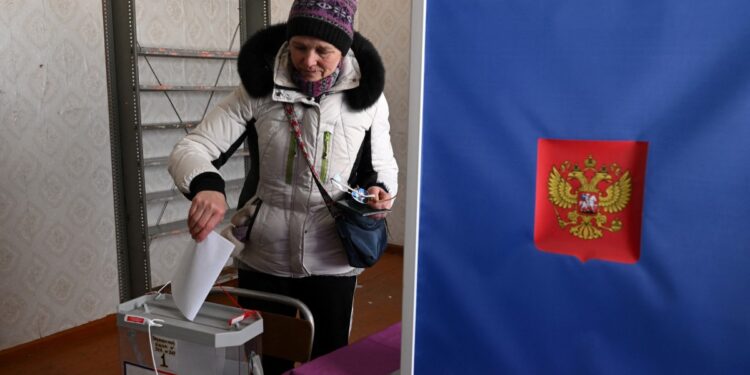Una mujer deposita su voto en un colegio electoral durante la votación anticipada para las elecciones presidenciales de Rusia en la aldea de Sennaya Guba, República de Karelia, el 10 de marzo de 2024. (Foto de NATALIA KOLESNIKOVA / AFP)