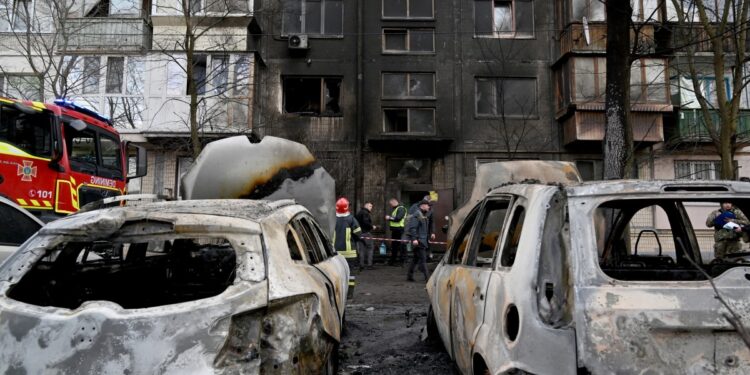 Ukrainian rescuers stand outside of a five-storey residential building after a missile attack, in Kyiv on March 21, 2024, amid the Russian invasion in Ukraine. - Ukrainian air defence forces shot down "about three dozen enemy missiles, including ballistic missiles, over Kyiv and in the vicinity of the capital," the city's military administration said on Telegram, adding that the raid had lasted three hours. (Photo by Sergei SUPINSKY / AFP)