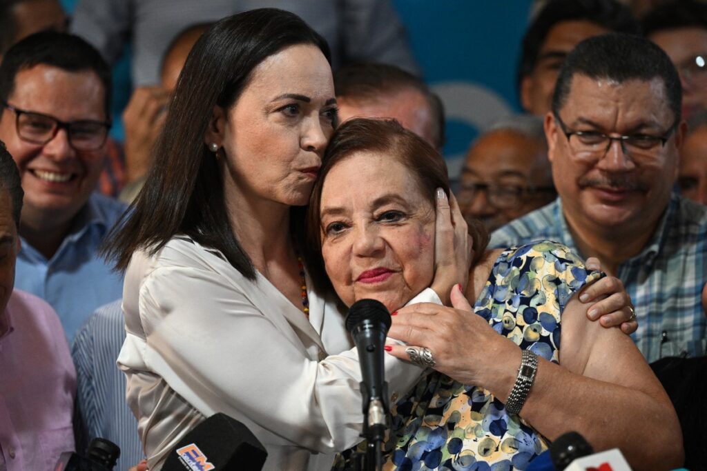 La líder opositora venezolana María Corina Machado (i) besa a su reemplazante para las próximas elecciones nacionales, Corina Yoris (d), durante una conferencia de prensa en Caracas, el 22 de marzo de 2024. - Machado anunció este viernes que Corina Yoris, filósofa y profesora universitaria Será la candidata que la represente en las elecciones presidenciales del próximo 28 de julio en las que se enfrentará al presidente Nicolás Maduro. (Foto de Federico Parra/AFP)