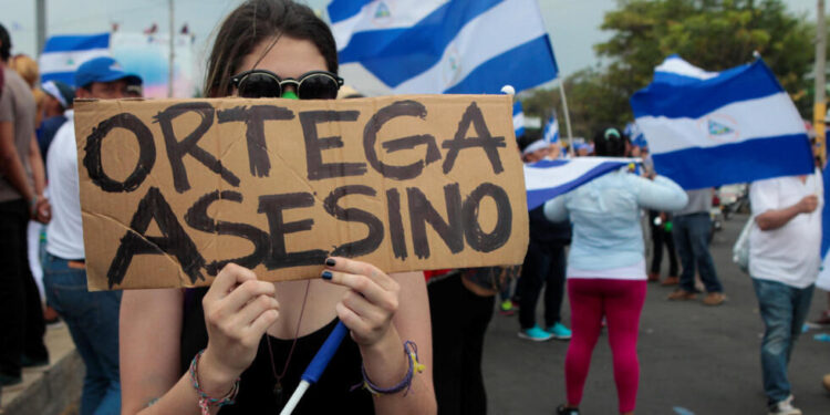 A demonstrator holds a sign that reads "Ortega Killer" during a protest march against Nicaraguan President Daniel Ortega's government in Managua, Nicaragua May 9, 2018. REUTERS/Oswaldo Rivas