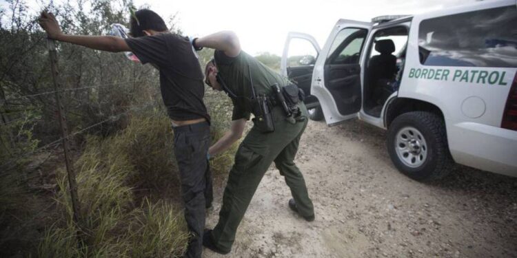 Policía fronteriza requisando migrantes en las fronteras.