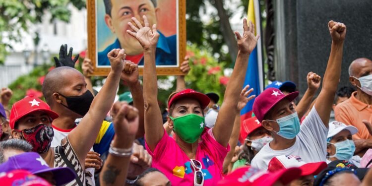 Los partidarios del gobierno del presidente venezolano Nicolás Maduro celebran los resultados de las elecciones legislativas del 6 de diciembre con un retrato del difunto presidente venezolano (1999-2013) Hugo Chávez en Caracas, el 12 de diciembre de 2020.