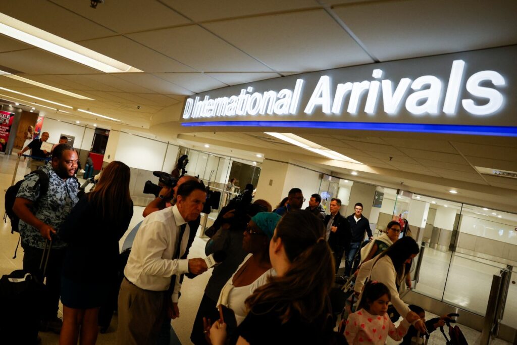 Un ciudadano haitiano-estadounidense (izq.) habla con los medios de comunicación después de llegar en un vuelo chárter desde Cap-Haitien al Aeropuerto Internacional de Miami en Miami, Florida, el 21 de marzo de 2024. - Estados Unidos también continúa evacuando a más ciudadanos, tomando algunos en helicóptero desde Puerto Príncipe hasta la vecina República Dominicana. (Foto de Marco BELLO / AFP)