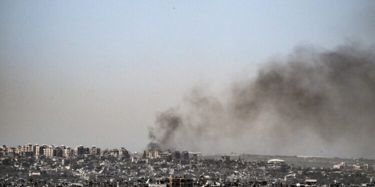 Esta fotografía tomada desde la frontera sur de Israel con la Franja de Gaza muestra humo ondeando detrás de los edificios destruidos debido a los ataques israelíes en el territorio palestino asediado el 2 de abril de 2024, en medio del conflicto en curso entre Israel y el grupo militante Hamás. (Foto de RONALDO SCHEMIDT / AFP)