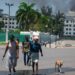 Mientras el humo sale del edificio del Ministerio de Finanzas detrás de ellos, la gente abandona la zona después de escuchar disparos de bandas armadas cerca del Palacio Nacional en Puerto Príncipe, Haití, el 2 de abril de 2024. - Más de 50.000 personas huyeron de Puerto Príncipe -Prince dentro de tres semanas el mes pasado cuando una explosión de violencia de pandillas sacudió la capital haitiana, dijo Naciones Unidas el 2 de abril de 2024. (Foto de Clarens SIFFROY / AFP)