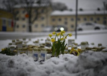 Se colocan velas y flores en la nieve frente a la escuela Viertola para rendir homenaje a las víctimas en Vantaa, en el norte de la capital finlandesa, Helsinki, el 3 de abril de 2024, un día después de que un niño de 12 años abriera fuego en el interior de la escuela. escuela, matando a un compañero de clase e hiriendo gravemente a otros dos niños. - Finlandia ondeará sus banderas a media asta el 3 de abril de 2024, para conmemorar el luto del país después de que un niño de 12 años abriera fuego en una escuela, matando a un compañero e hiriendo gravemente a otros dos en la ciudad de Vantaa. (Foto de Olivier MORIN / AFP)