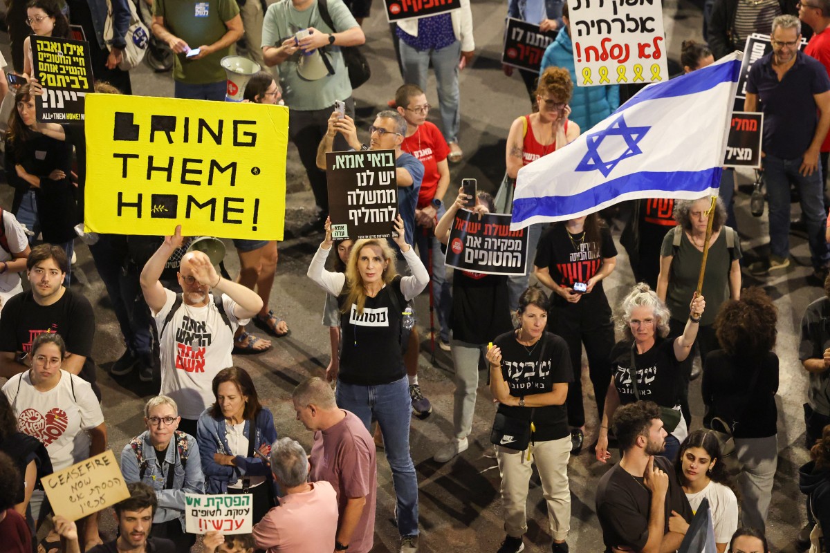 Familiares y partidarios de rehenes tomados cautivos por militantes palestinos en Gaza durante los ataques del 7 de octubre, sostienen pancartas y ondean banderas nacionales durante una manifestación pidiendo su liberación, en la ciudad costera israelí de Tel Aviv el 27 de abril de 2024, en medio del conflicto en curso. entre Israel y el grupo militante Hamás. (Foto de JACK GUEZ / AFP)