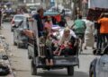 Un hombre, una mujer y niños viajan en la parte trasera de un triciclo cargado con pertenencias y otros artículos mientras huyen con destino a Khan Yunis, en Rafah, en el sur de la Franja de Gaza, el 11 de mayo de 2024, en medio del conflicto en curso en el territorio palestino entre Israel. y Hamás. (Foto de AFP)
